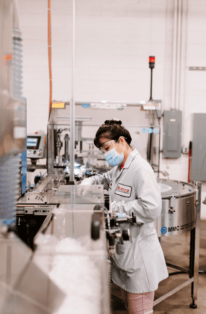 woman in white lab coat in front of microscope